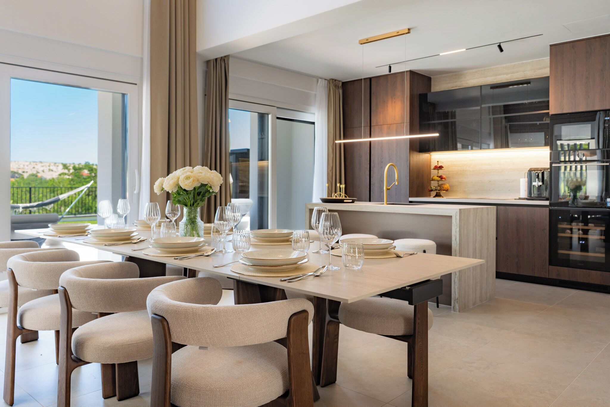 Een moderne eetruimte met een lange tafel, stoelen en een bloevas.