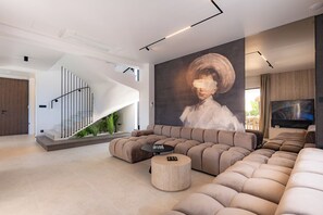 Una sala de estar moderna con un sofá modular curvo, una mesa de centro redonda y una escalera de diseño único.