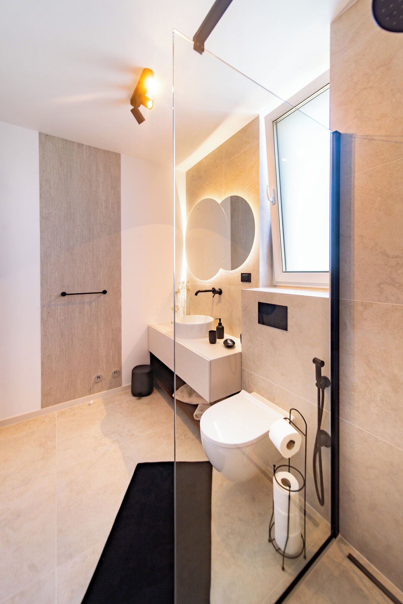 A modern bathroom with a glass partition, a white sink, a mirror, and a toilet.