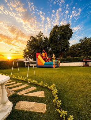 A grassy outdoor area with a colorful inflatable slide and a white table.
