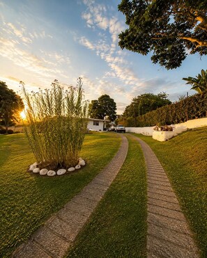 A pathway leading to a house with a garden and a clear sky.