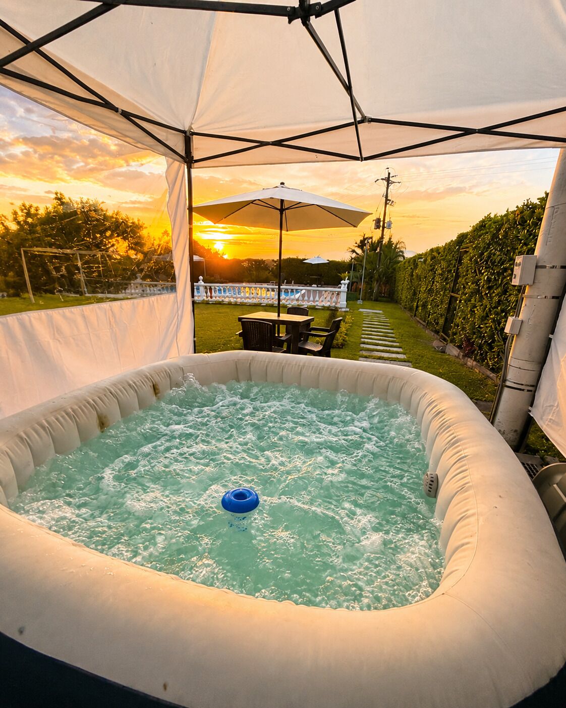 An inflatable hot tub under a canopy with a sunset view.
