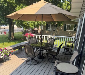 A covered outdoor seating area with a table and chairs, a potted plant, and a view of the house. - Cozy lake cabin with 50 Amp for RVs on Pelican Lake, with private dock. (Detroit Lakes)