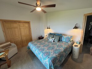 A bedroom with a bed, a ceiling fan, a nightstand, a chair, and a wardrobe. - Cozy lake cabin with 50 Amp for RVs on Pelican Lake, with private dock. (Detroit Lakes)