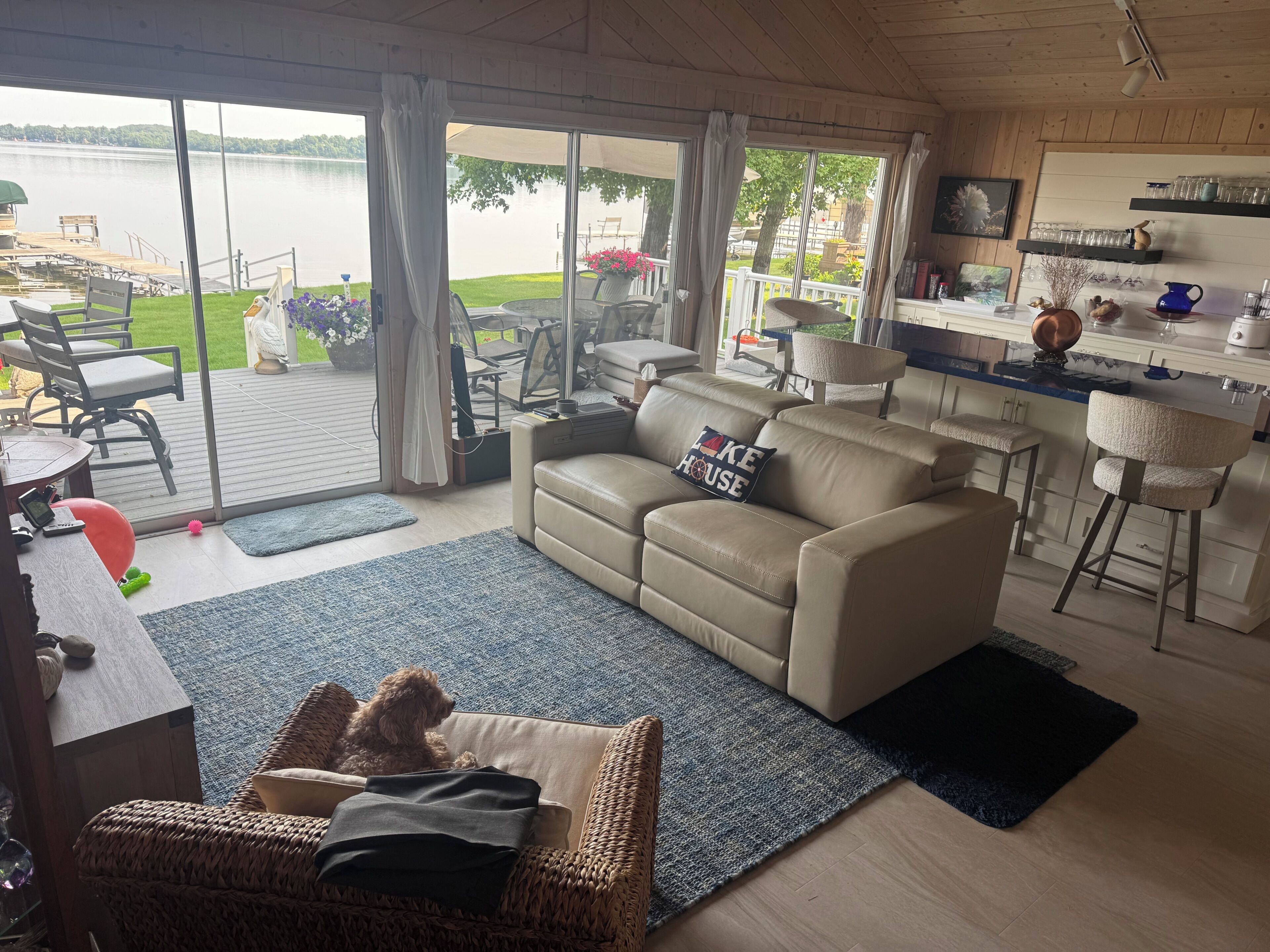 A cozy living room with a sofa, a wicker chair, and a dog.