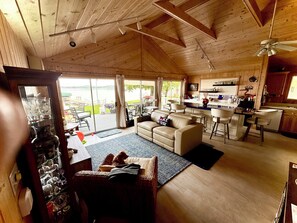 A spacious living area with a sofa, a dining table, and a kitchen in the background. - Cozy lake cabin with 50 Amp for RVs on Pelican Lake, with private dock. (Detroit Lakes)