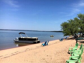 A beach with a boat docked, chairs, and a clear sky. - Peaceful Lakefront Cabin with Loft, Beach Access & Sunset Views in Buchanan Dam, Texas (Buchanan Dam)