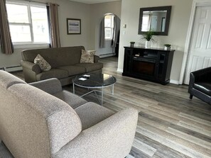A living room with a sofa, a coffee table, and a fireplace. - Middleton Motel and Suits (Middleton)