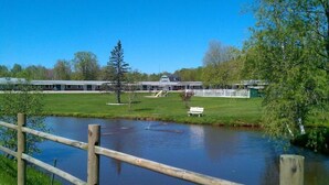 A building with a large lawn and a pond in front. - Middleton Motel and Suits (Middleton)