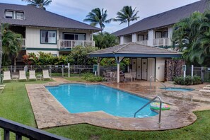 A sparkling pool awaits you in a lush tropical courtyard, surrounded by swaying palms and cozy vacation homes. Relax on the sun loungers or gather under the shaded pavilion for a perfect island retreat. - Regency at Poipu Kai 823 | Spacious 3BR Townhome Near Poipu Beach (Koloa)