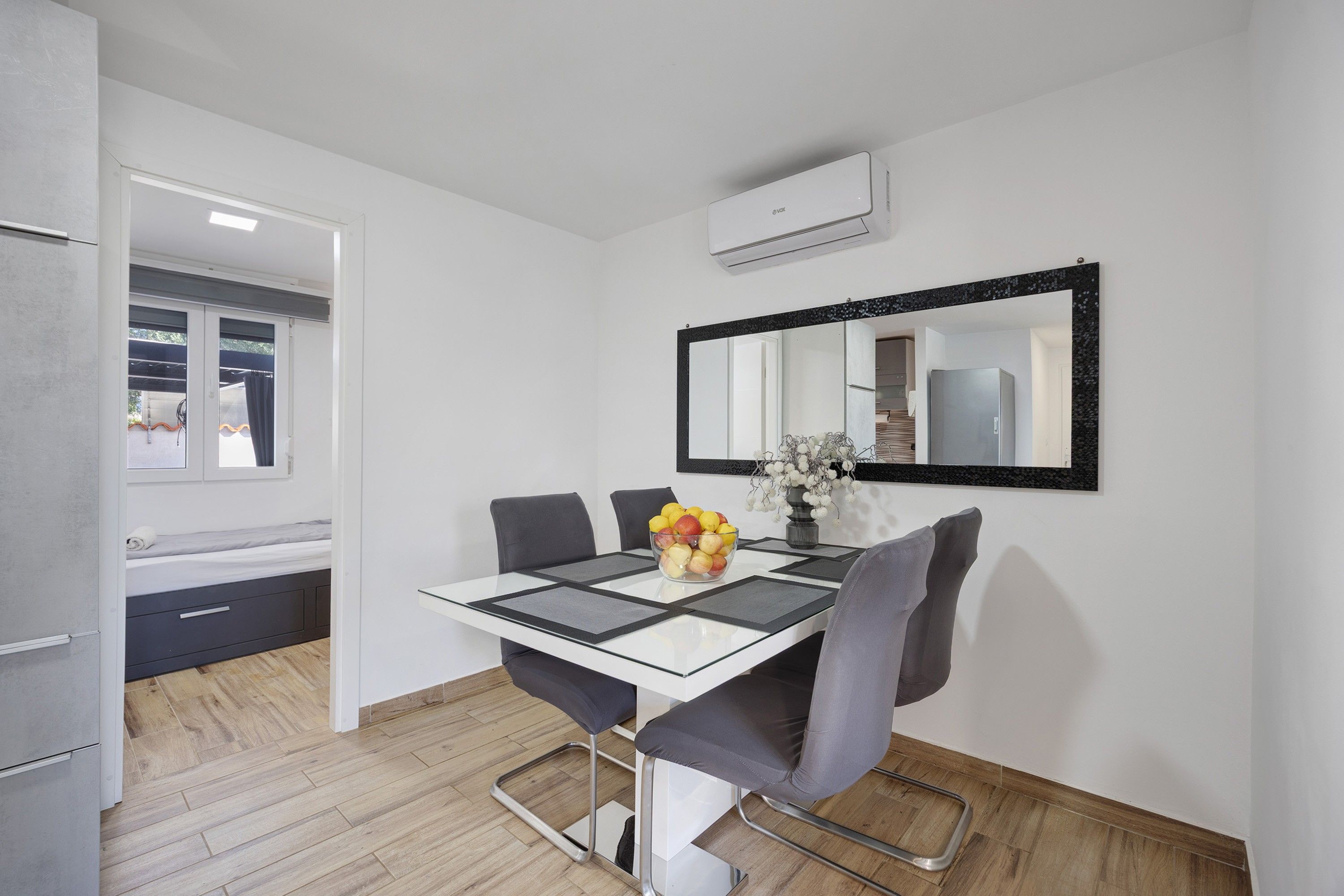 Una cocina moderna con refrigerador integrado, un comedor con mesa y sillas, y un espejo grande en la pared.