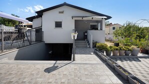 Uma casa moderna de dois andares com entrada coberta, uma pequena varanda e calçada pavimentada.