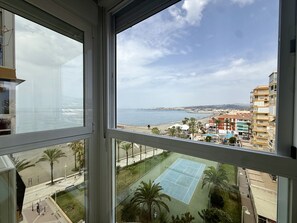 A view from a window overlooking a beach, a tennis court, and a cityscape with buildings. - ALGARROBO BEACH 11, Algarrobo Costa (Algarrobo Costa)