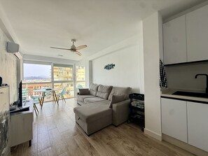 A modern apartment with a sofa, dining table, and kitchen area. - ALGARROBO BEACH 11, Algarrobo Costa (Algarrobo Costa)