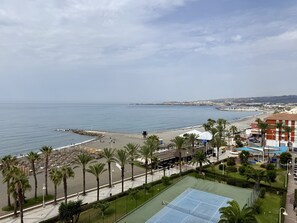 A coastal view with a beach, palm trees, and a tennis court. - ALGARROBO BEACH 11, Algarrobo Costa (Algarrobo Costa)