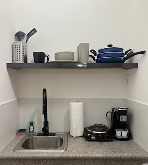 A kitchen with a sink, a coffee maker, a kettle, and various kitchen utensils on the countertop. - Stay Near Everything & Beach - Walkable Condado (San Juan)