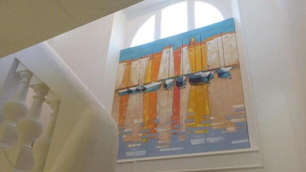 A staircase with a painting of sailboats on the wall.