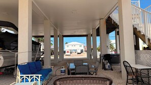 An outdoor covered area with a sofa, chairs, and a grill. - Harmony: 3BR/2BA Cozy Retreat w/ Spa, Sun Deck & Boat Parking (Marathon)