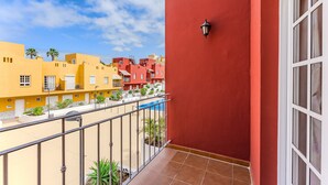 Een balkon met uitzicht op een zwembad en omliggende gebouwen.