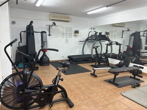 A gym with exercise equipment, a fan, and a mirror.