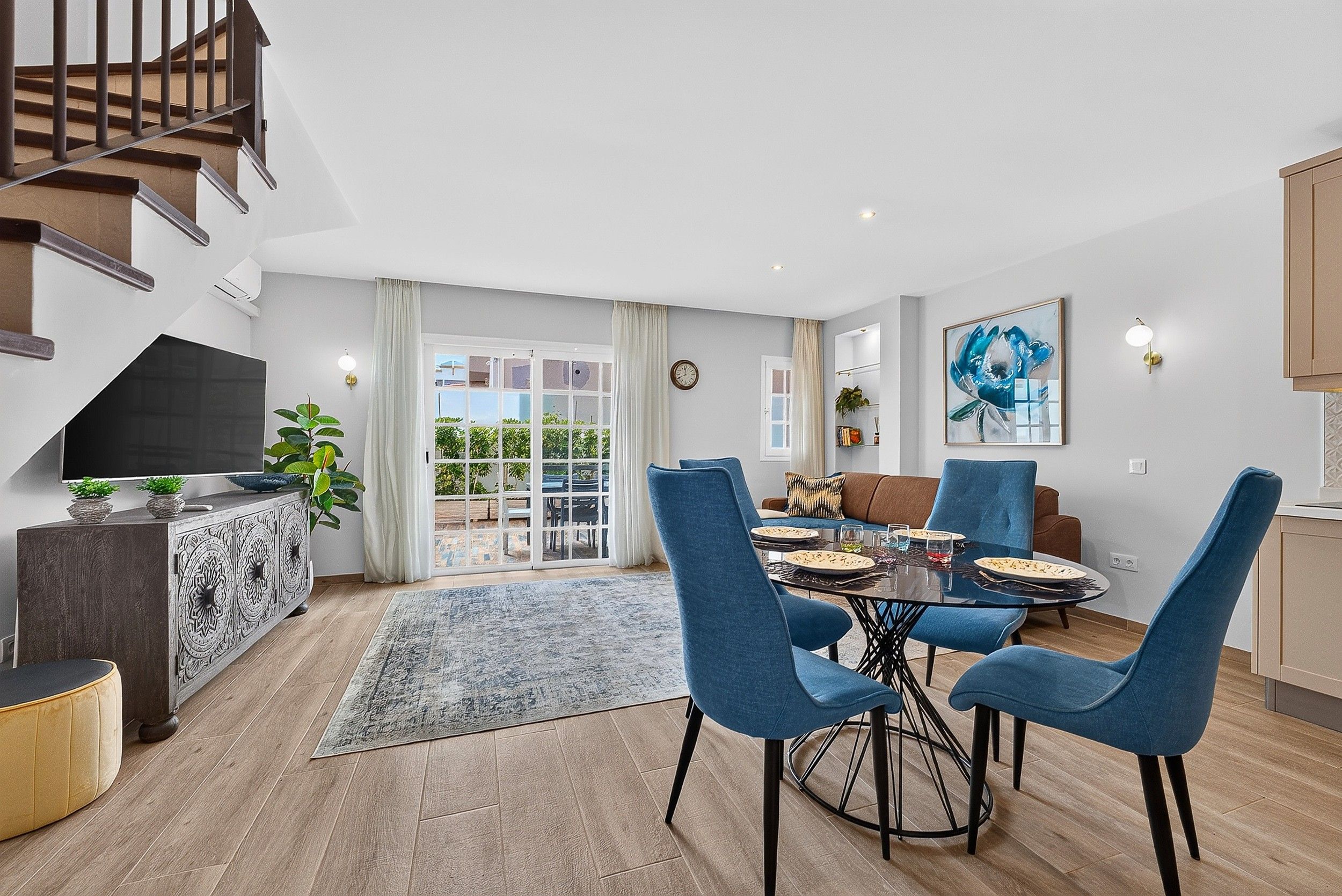 Una sala de estar moderna con comedor, una escalera y vistas al exterior.