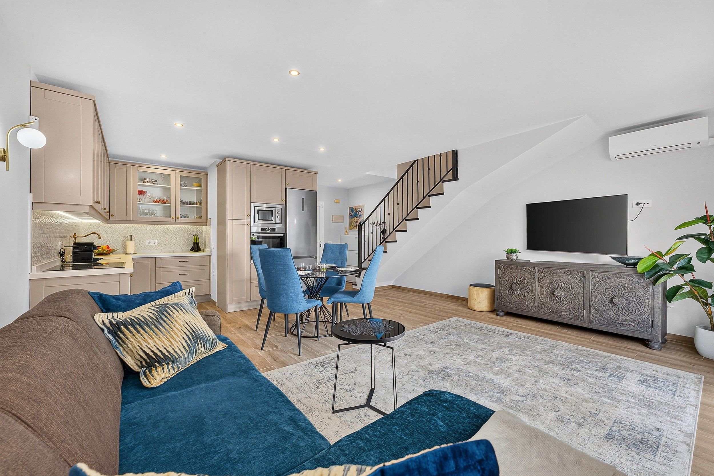 Un espacio habitable moderno con sofá, comedor, cocina y escalera.