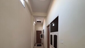 A narrow hallway with a door at the end, a light switch, and a small vent on the ceiling. - Ollection O Sector 95B Gurgaon (Gurugram)
