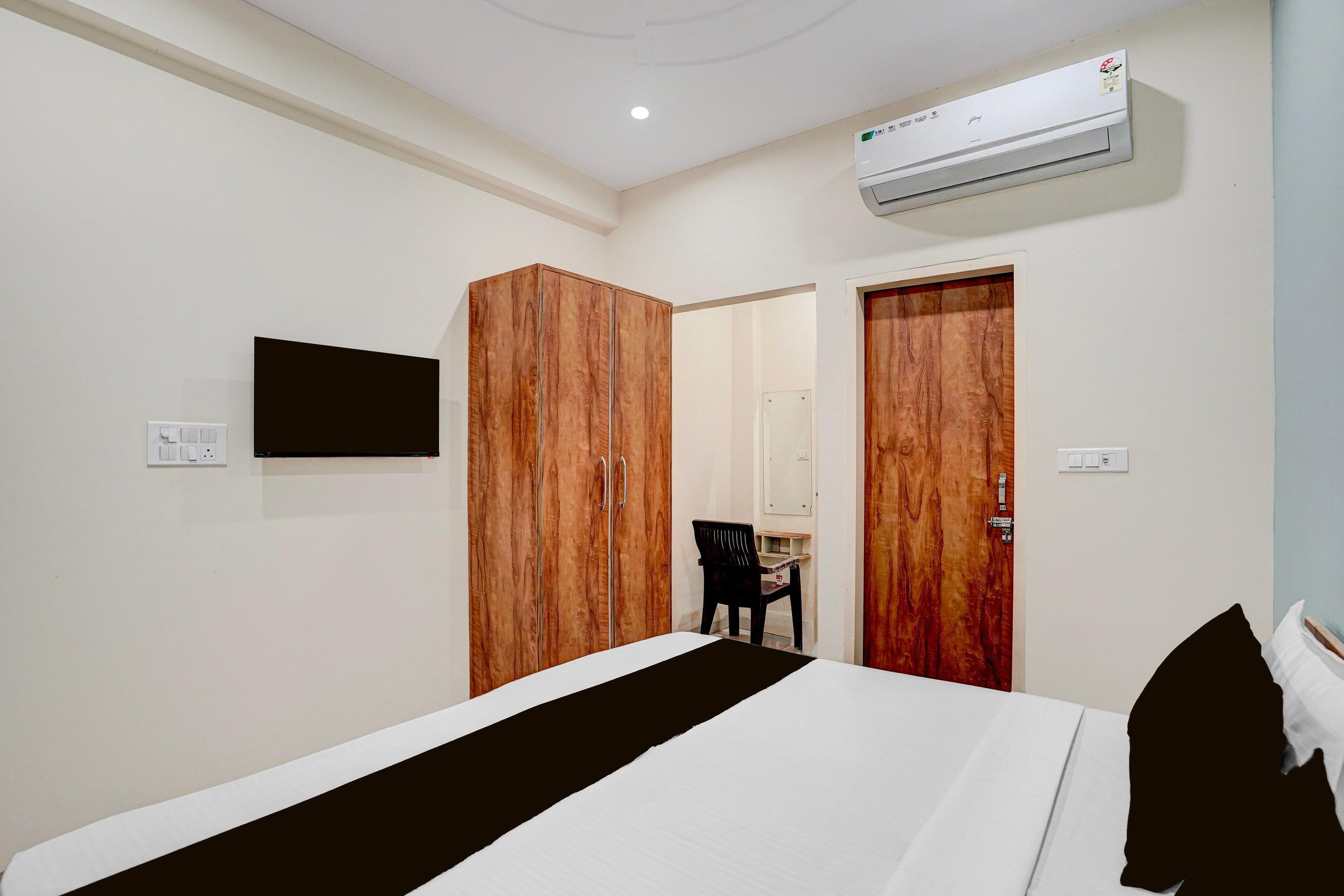 A hotel room with a bed, wardrobe, and a television mounted on the wall.