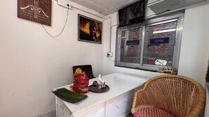 A room with a white counter, a wicker chair, a Buddha painting, and a window with a sign. - Ollection O Sector 95B Gurgaon (Gurugram)