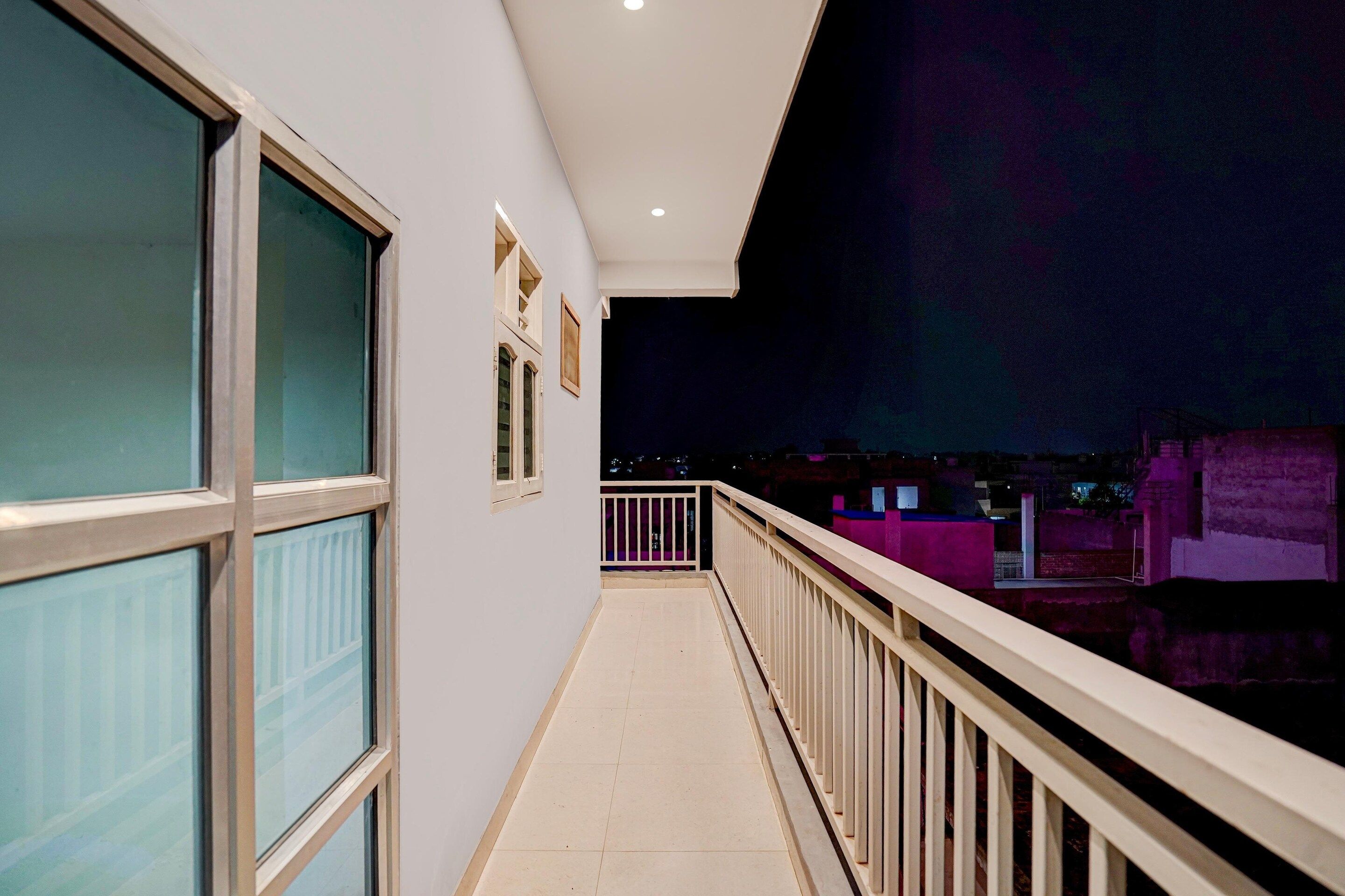 A corridor with a balcony, large windows, and a view of the night sky.