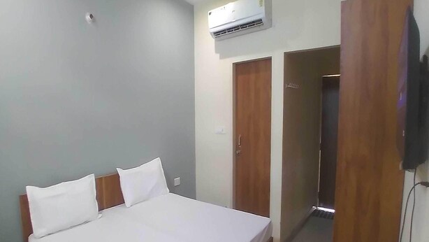 A bedroom with a bed, a bedside table, an air conditioner, and a wardrobe. - Ollection O Sector 95B Gurgaon (Gurugram)