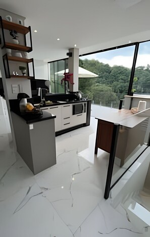 Uma cozinha moderna com ilha central, eletrodomésticos embutidos e uma grande janela com vista para o exterior.
