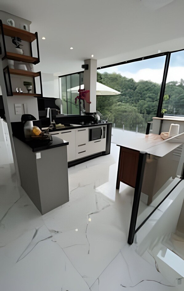 A modern kitchen with a central island, built-in appliances, and a large window offering a view of the outdoors.
