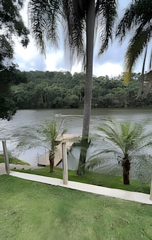 A river with a concrete walkway and palm trees.