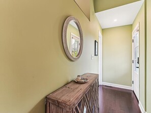 Ein Flur mit einem Holztischchen und einem Spiegel an der Wand.