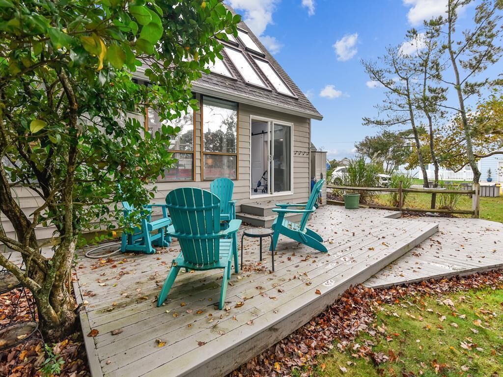 Une terrasse couverte avec des sièges d’extérieur, et une maison en arrière-plan.