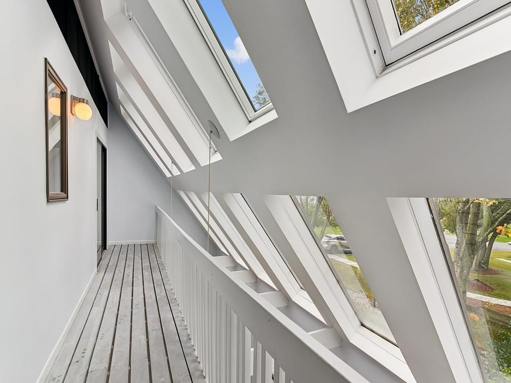 A narrow corridor with skylights and a wooden floor.