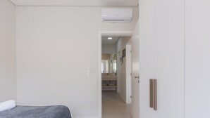 Een slaapkamer met een bed, een kledingkast en een airconditioning.