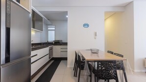 Een moderne keuken met roestvrijstalen apparatuur, een eethoek met een tafel en stoelen, en een klein aanrecht met een magnetron.