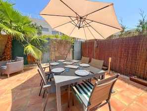 An outdoor patio with a table set for dining, surrounded by chairs and an umbrella. - Modern townhouse in Dénia – all-inclusive (Denia)