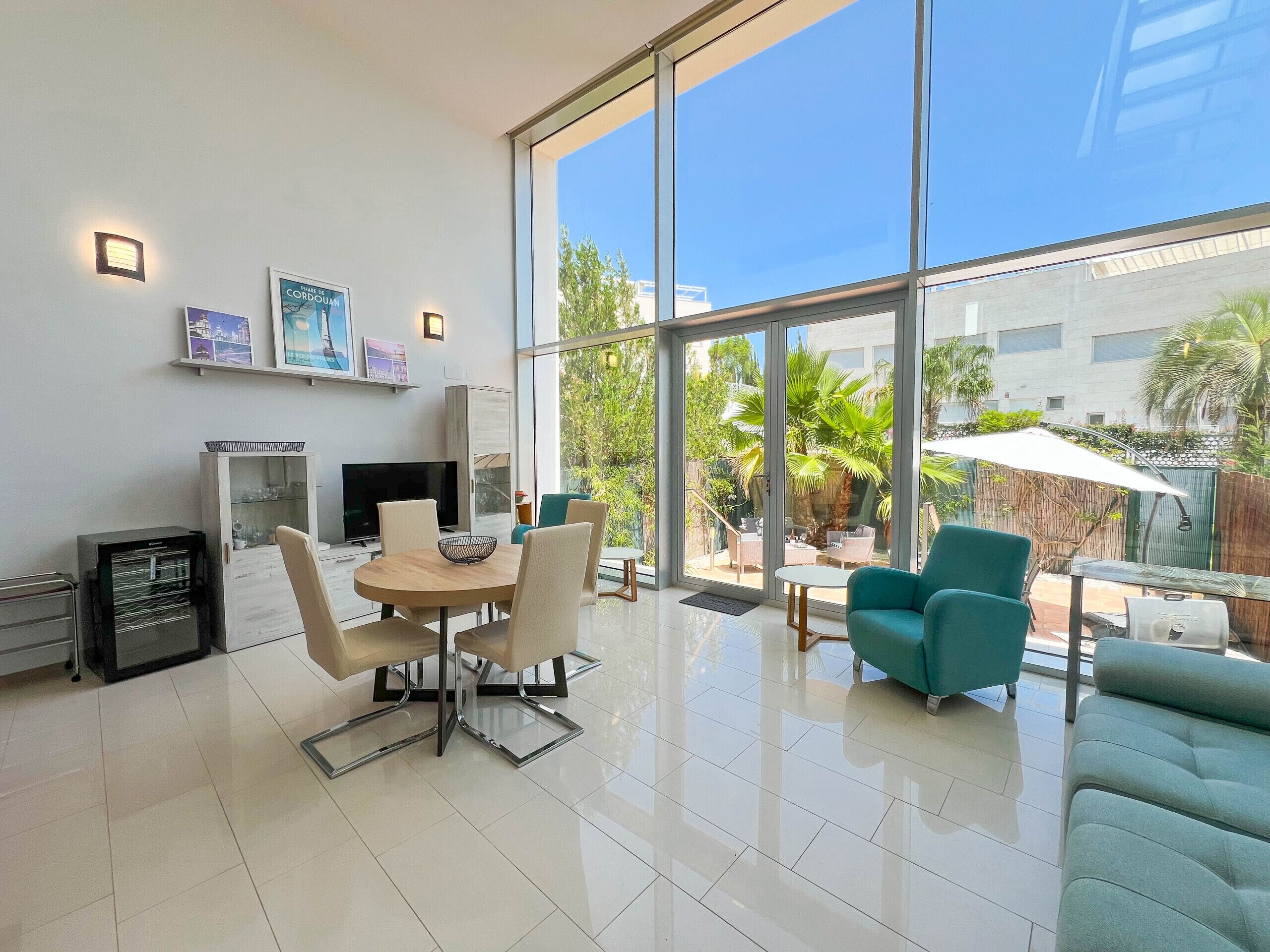 A modern living room with a dining area, large windows, and a view of the outdoors.