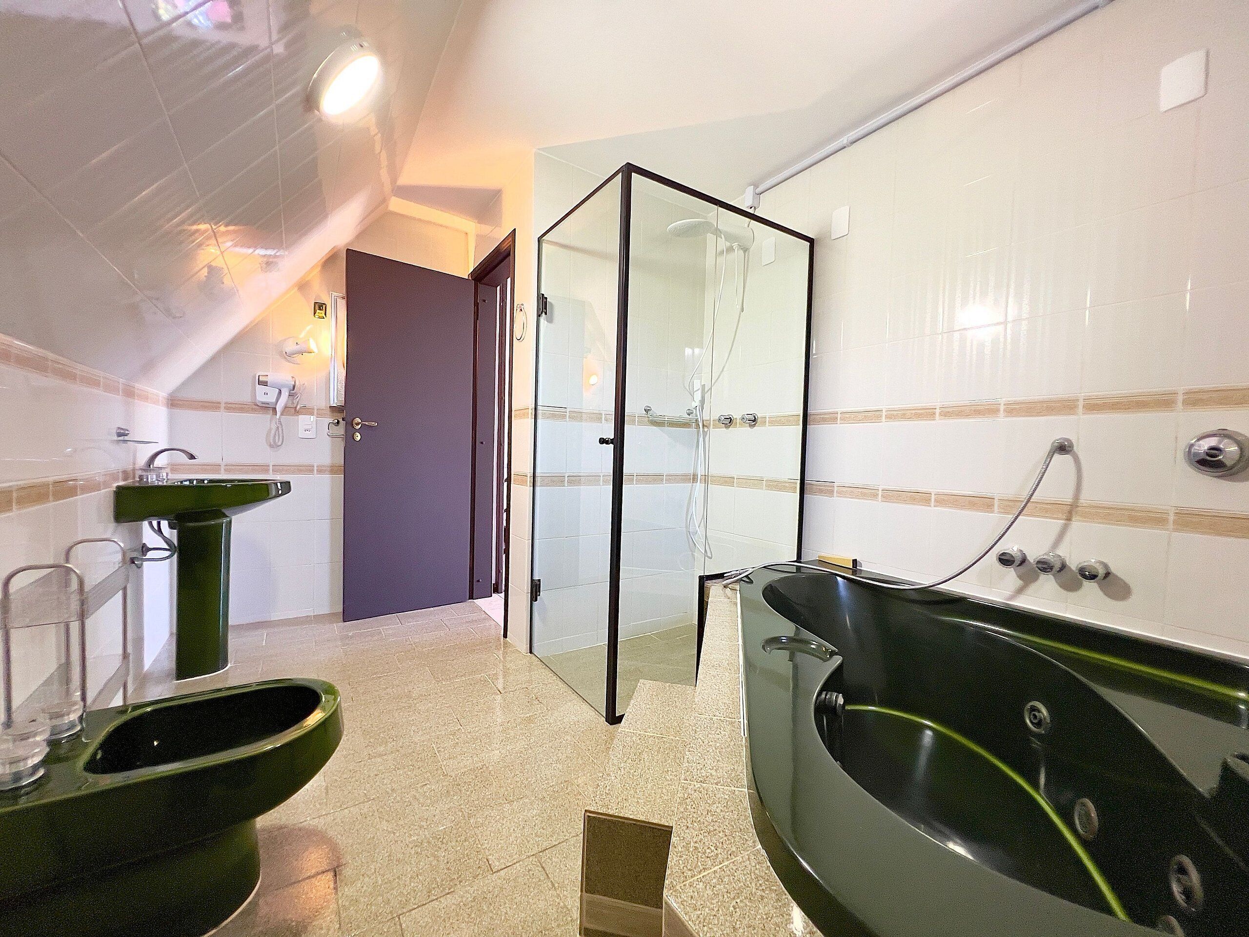 Ein Badezimmer mit einem grünen Waschbecken, einer Duschkabine und einer schwarzen Badewanne.