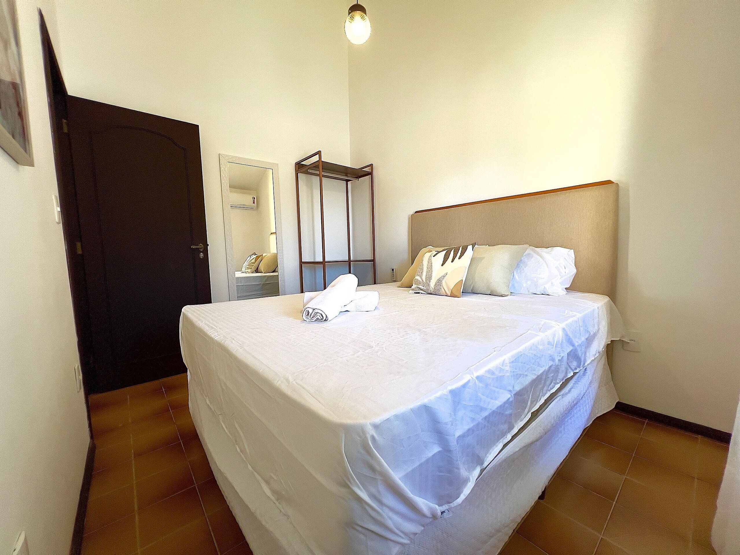 A hotel room with a bed, a wardrobe, a mirror, and a door.