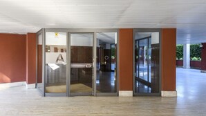 A spacious indoor area with a glass door entrance, a visible toilet, and a corridor leading to another room. - Lodi, 65 – Your Milan Base (Milan)