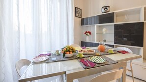 A dining area with a table set for breakfast, including fruits, a pitcher, and a vase with flowers. - Lodi, 65 – Your Milan Base (Milan)