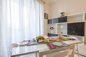 A dining area with a table set for breakfast, including fruits, a pitcher, and a vase with flowers. - Lodi, 65 – Your Milan Base (Milan)