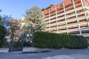 Ein mehrgeschossiges Wohngebäude mit Balkonen, einem verschlossenen Eingang und einer gepflegten Hecke.