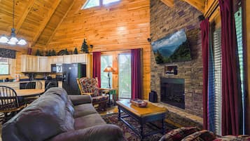 A cozy cabin interior with a living room, kitchen, and fireplace.
