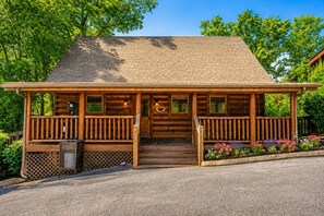 A log cabin with a porch, steps, and a small garden.