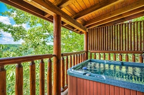 A wooden deck with a hot tub, surrounded by lush greenery and a clear sky. - A Time to Remember -Private Hot Tub • Game Room • Resort Pools (Sevierville)